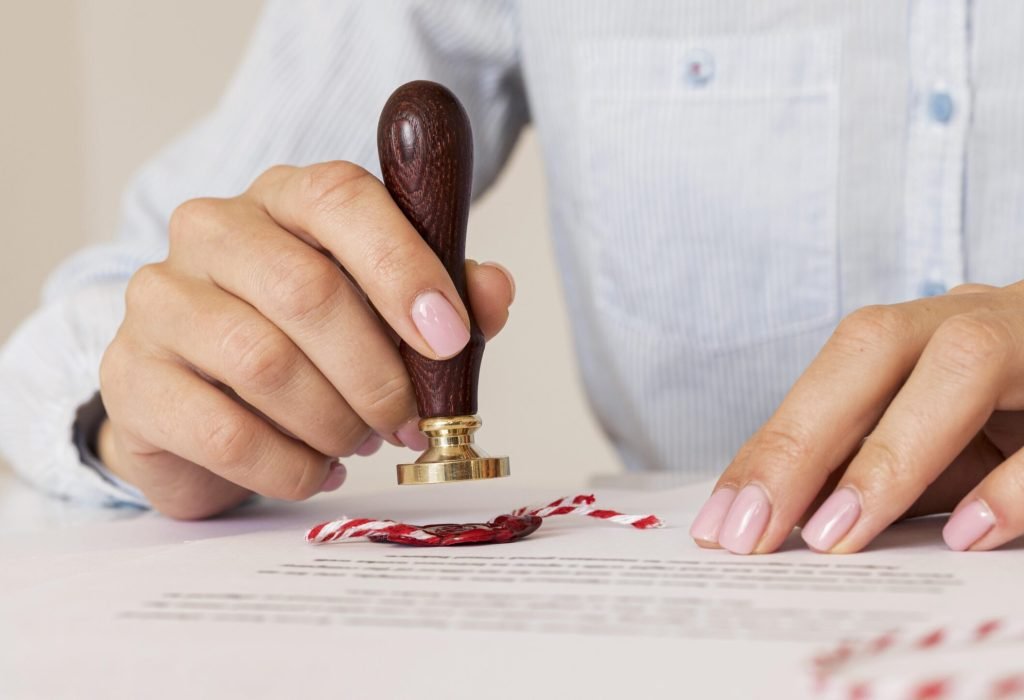 person-using-wax-seal-blurred-certificate